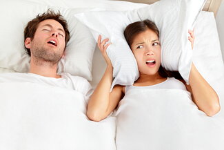 man snoring, woman covering ears with pillow trying to sleep, Tomball, TX sleep apnea